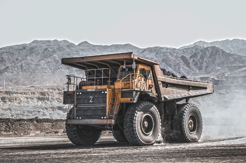A loaded haul truck driving across an open pit.