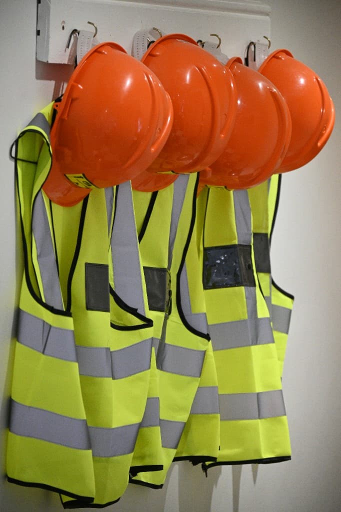 Hard hats and high-visibility vests hanging ready for a shift.