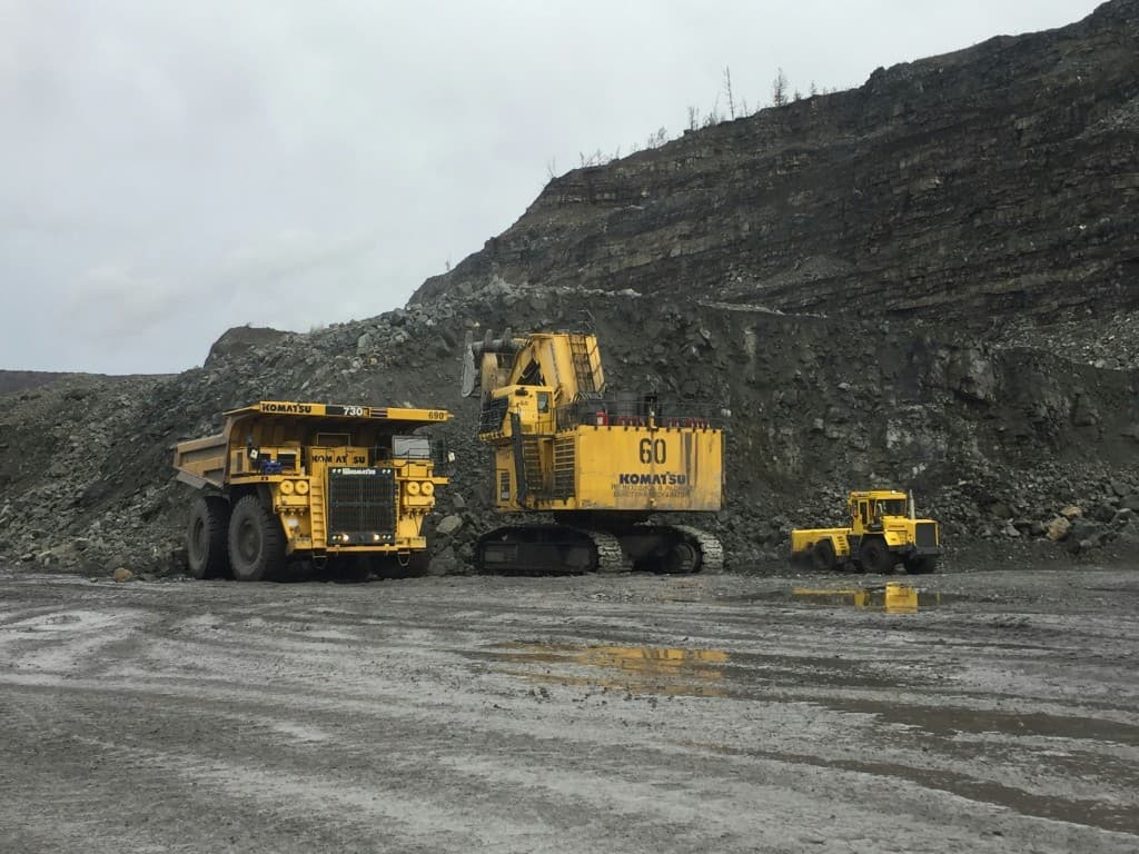 An excavator, haul truck and loader on a pit bench.